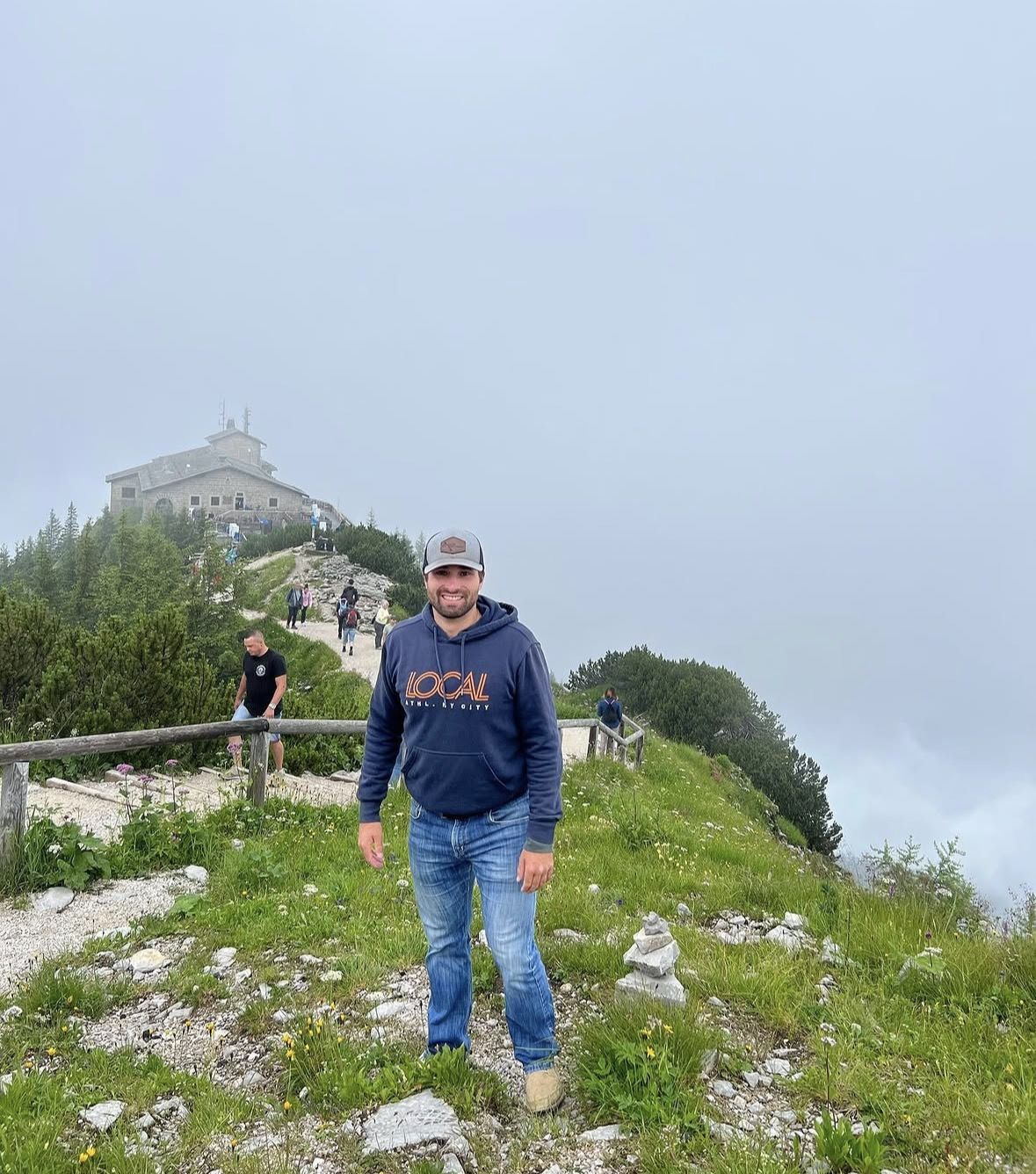 Hiker with daypack standing on Eagle's Nest summit terrace wearing a waterproof jacket